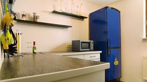 A kitchen with a blue refrigerator, a microwave, and a wine bottle on the counter. - Apartment 'Bäuerle' with Private Terrace, Private Garden and Wi-Fi (Schönwald)