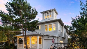 A two-story house with a porch, a garage, and a flag. - 30A Luxury-5 Bed/Sleeps 12-Bikes-Golf Cart-Pools-Tennis/Pickleball Beach Service (Santa Rosa Beach)