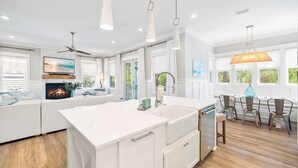 A modern kitchen with a central island, white cabinetry, and a dining area with three chairs. - 30A Luxury-5 Bed/Sleeps 12-Bikes-Golf Cart-Pools-Tennis/Pickleball Beach Service (Santa Rosa Beach)