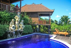 Una piscina al aire libre, sombrillas, sillones reclinables de piscina