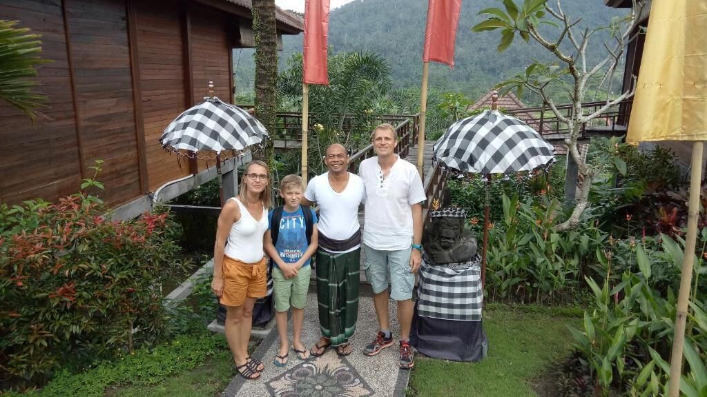A group of people standing in a garden with checkered umbrellas, a wooden building, and a staircase leading to a higher level.