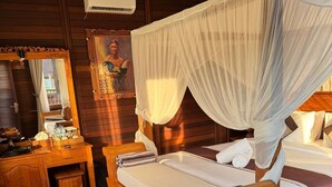 Una habitación de madera con una cama bajo un dosel, un escritorio de madera, un espejo y un cuadro en la pared.