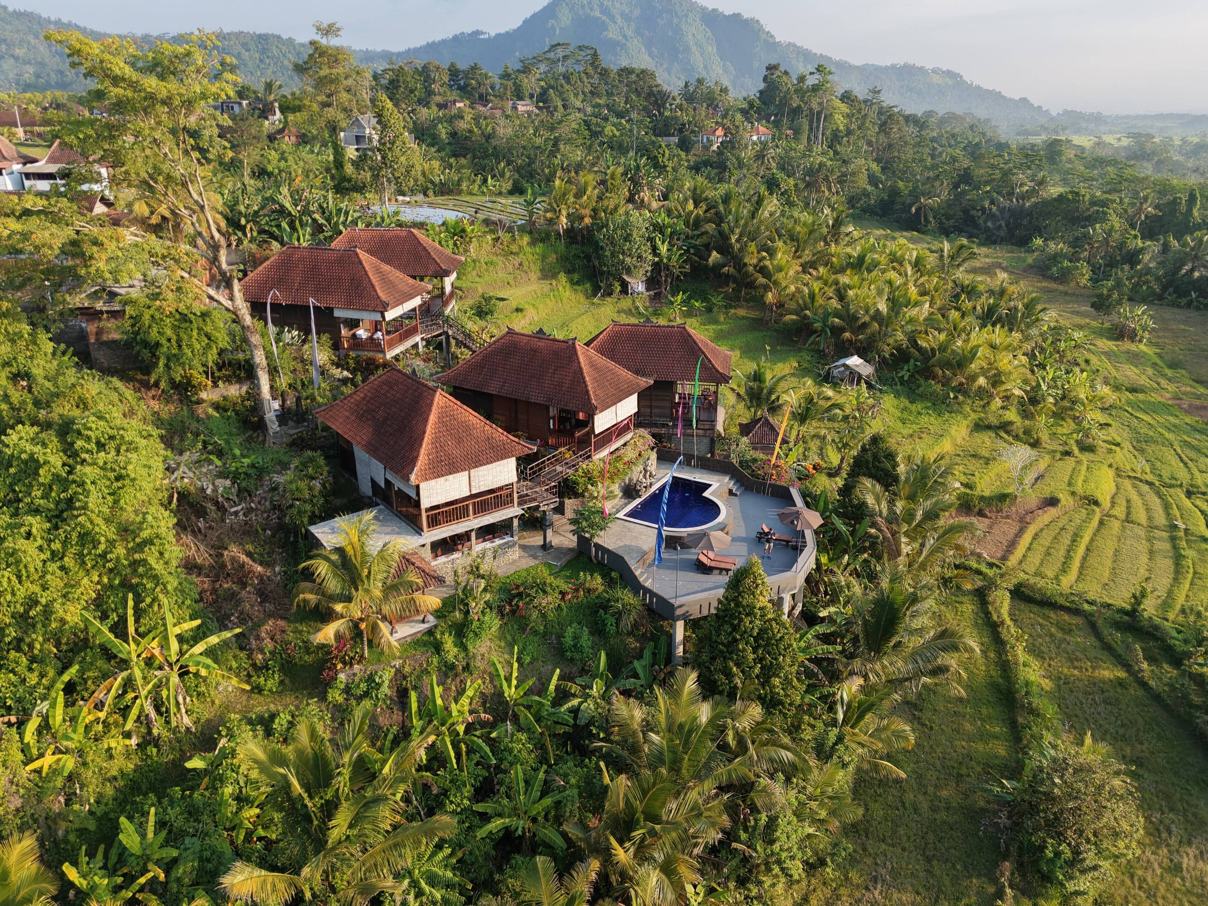 Un resort tropical con varias construcciones, una piscina y abundante vegetación.