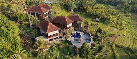 A tropical resort with multiple buildings, a swimming pool, and lush greenery.