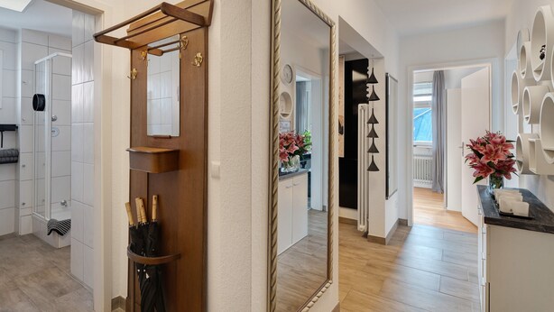 A hallway with a wooden door, a large mirror, and a wall-mounted towel rack. - Holiday Apartment 'Baden - Baden International' with Wi-Fi (Baden-Baden)