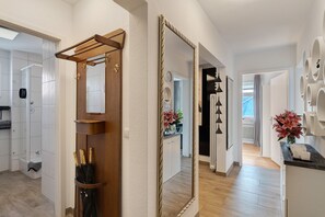 Un pasillo con una puerta de madera, un espejo grande y un perchero de toallas en la pared.