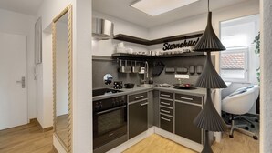 A modern kitchen with a built-in oven, a sink, and a countertop with kitchenware. - Holiday Apartment 'Baden - Baden International' with Wi-Fi (Baden-Baden)