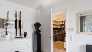 A modern interior with a white dresser, a sculpture, and a view into a kitchen area. - Holiday Apartment 'Baden - Baden International' with Wi-Fi (Baden-Baden)