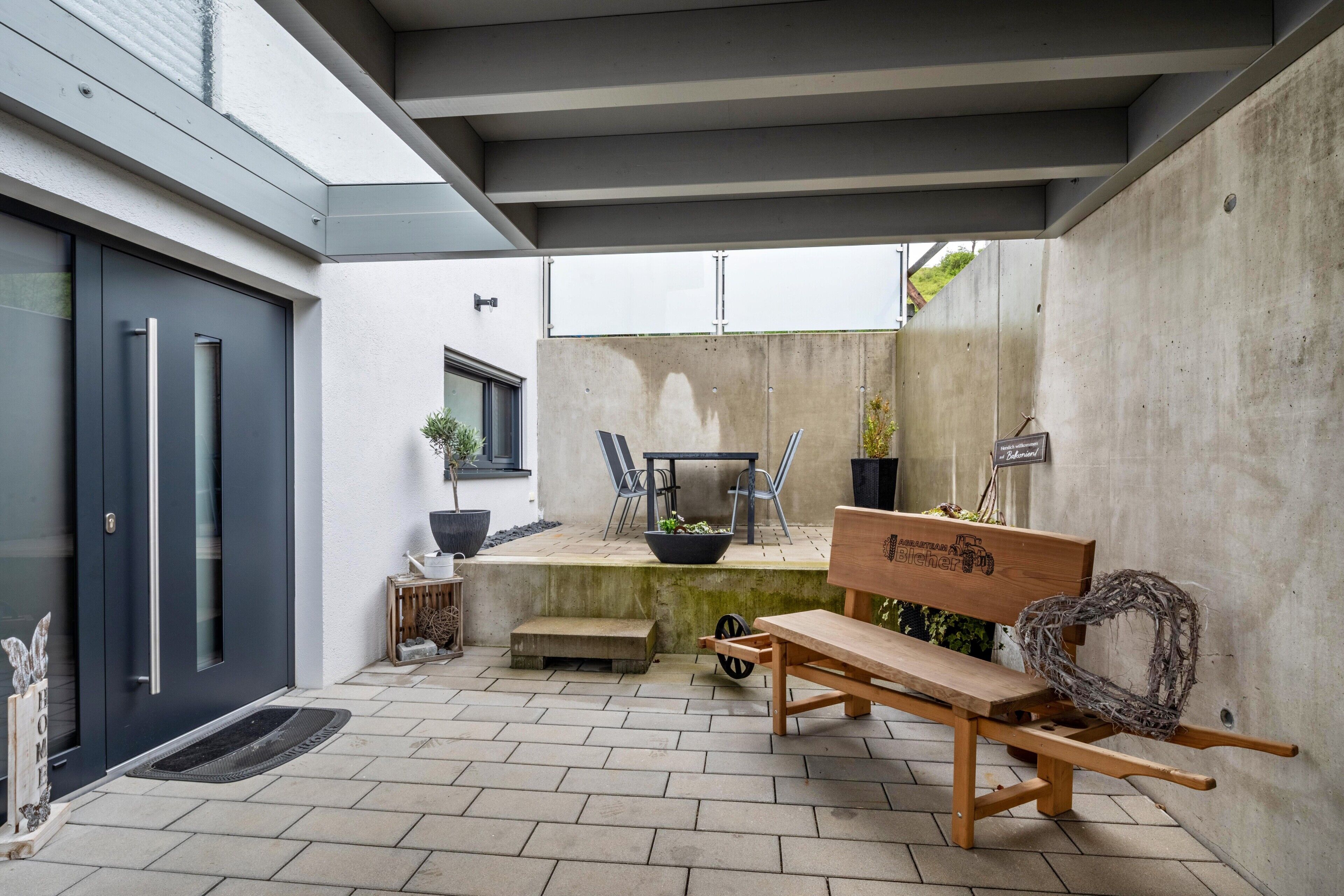 A modern outdoor patio with a bench, a table, and chairs.