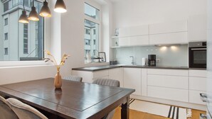 A modern kitchen with white cabinetry, a dark wooden dining table, and pendant lights. - Timeless Home: Stylish Oasis Near the Lake (Bregenz)