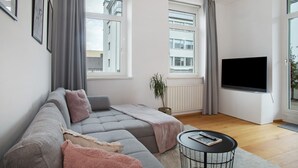 A modern living room with a sofa, a flat-screen TV, and a potted plant. - Timeless Home: Stylish Oasis Near the Lake (Bregenz)