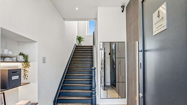 A staircase leading to a room with a door labeled '4 Quellstraße.' - Timeless Home: Stylish Oasis Near the Lake (Bregenz)