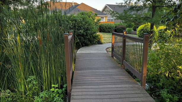 A wooden pathway leading to a residential area with houses and lush greenery. - Plumberry Cottage in Charming Neighborhood (College Place)