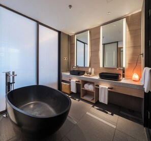 Ein modernes Badezimmer mit einer großen schwarzen Badewanne, einem Doppelwaschtisch und einem großen Spiegel.