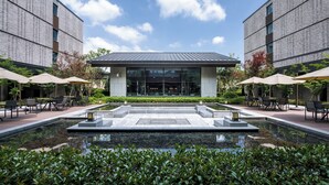 A modern building with a central courtyard featuring a water feature, surrounded by outdoor seating areas and greenery. - HENTIQUE MANNA TANGSHAN (Nanjing)