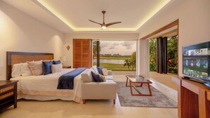 Un dormitorio moderno con una cama grande, un sofá, un televisor y un balcón con vistas a un lago.