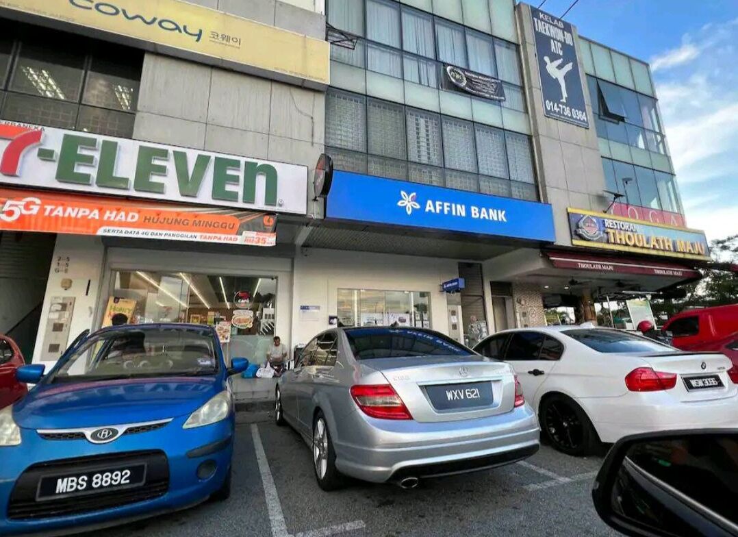 Een gebouw met verschillende winkels, waaronder een 7-Eleven, een Affin Bank en een restaurant.