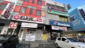 Um edifício com várias lojas, incluindo uma clínica dentária, uma Domino's Pizza e um centro de saúde.