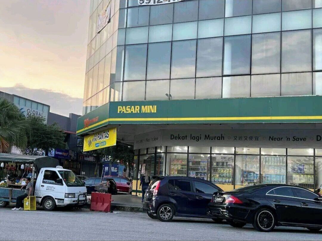 A building with a green sign reading "PASAR MINI" and a storefront with glass windows.