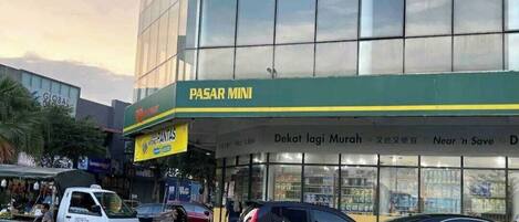 A building with a green sign reading "PASAR MINI" and a storefront with glass windows.