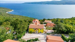 A yellow house with a red roof surrounded by greenery and a large body of water. - Seaview House Helena - Apartment 1, Plomin, Croatia (Plomin)