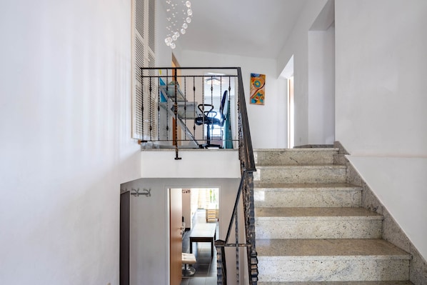 A staircase with a handrail and a door leading to a room with a dining table and chairs. - Seaview House Helena - Apartment 1, Plomin, Croatia (Plomin)