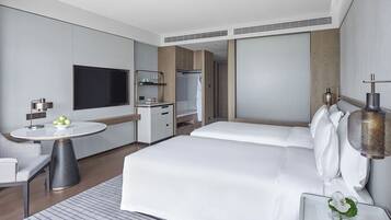 Una habitación de hotel moderna con una cama grande, un escritorio con lámpara, un televisor y un armario.