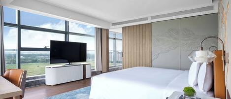 Una habitación de hotel moderna con una cama grande, un televisor de pantalla plana, un escritorio y vistas a la ciudad.