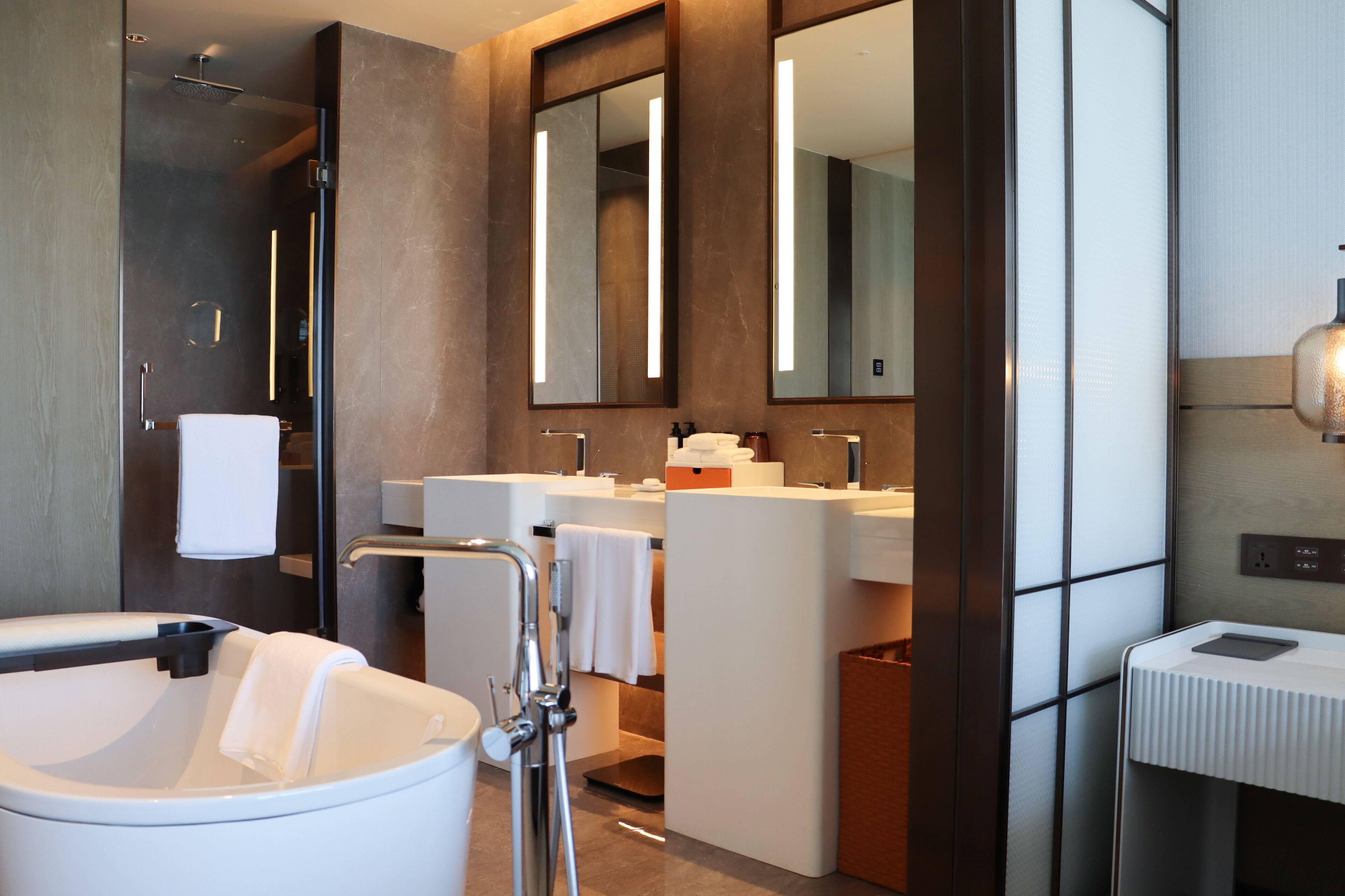 A modern bathroom with a bathtub, a large mirror, a vanity with a sink, and a shower area.