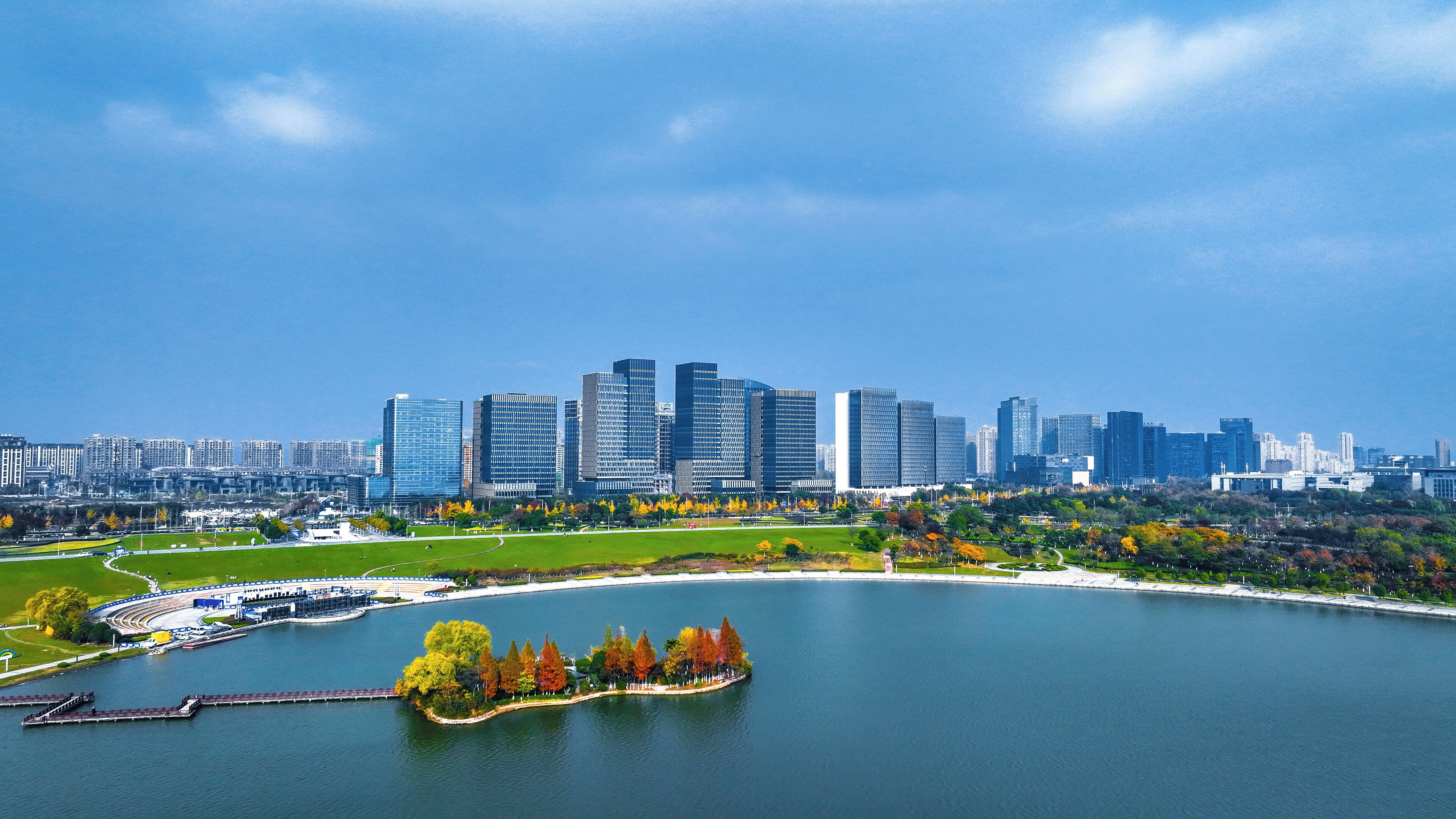Un paysage urbain avec des gratte-ciel modernes, un parc au bord de l’eau et un lac.