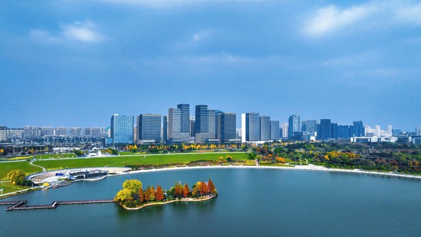 Un paisaje urbano con rascacielos modernos, un parque frente al agua y un lago.