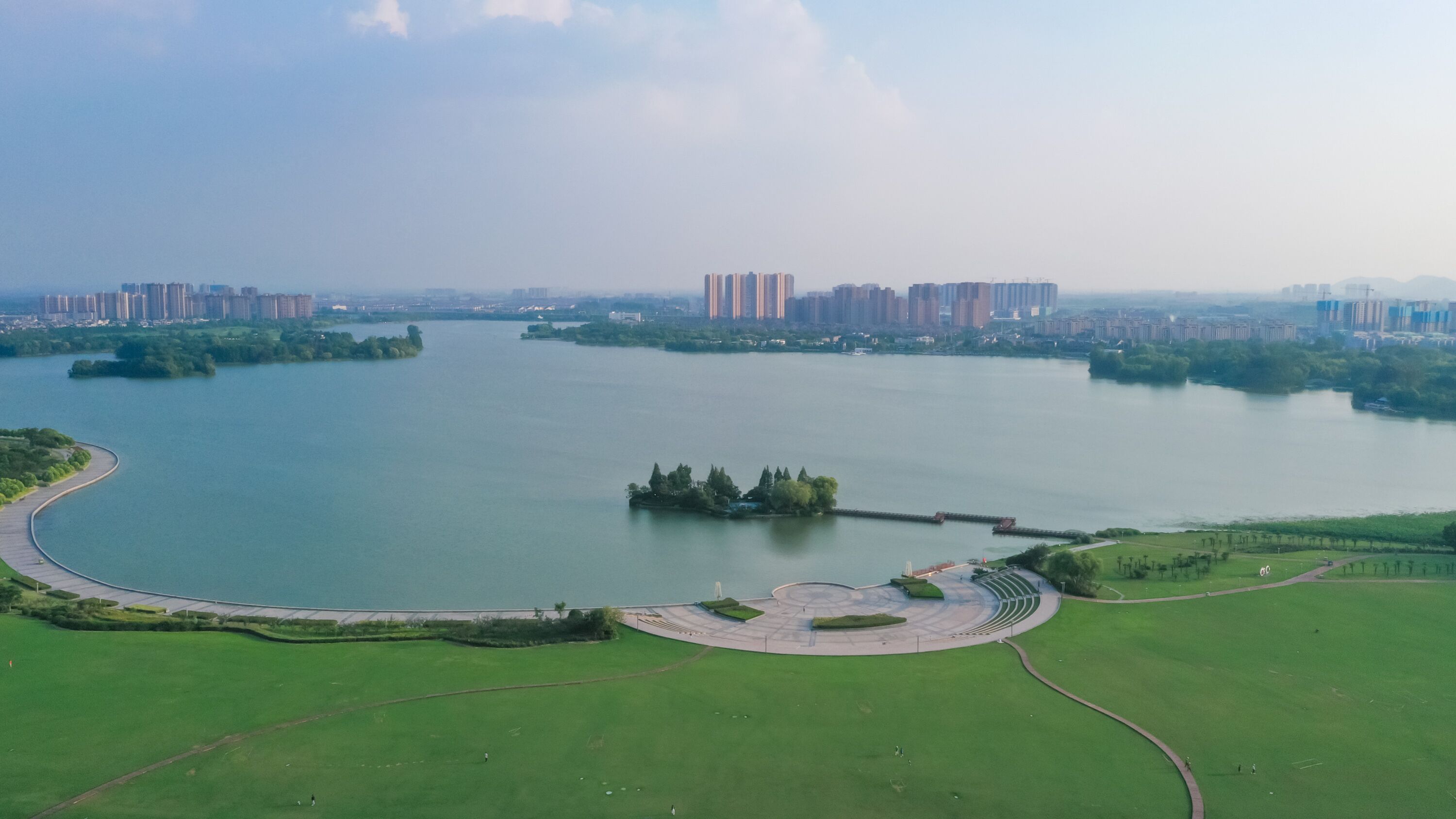 A large body of water with a park area and a curved road.