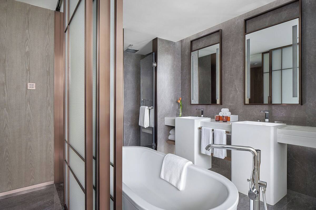 A modern bathroom with a freestanding bathtub, a glass shower enclosure, and a vanity with a large mirror.