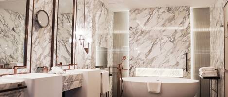 A modern bathroom with marble walls, a freestanding bathtub, and a large mirror.