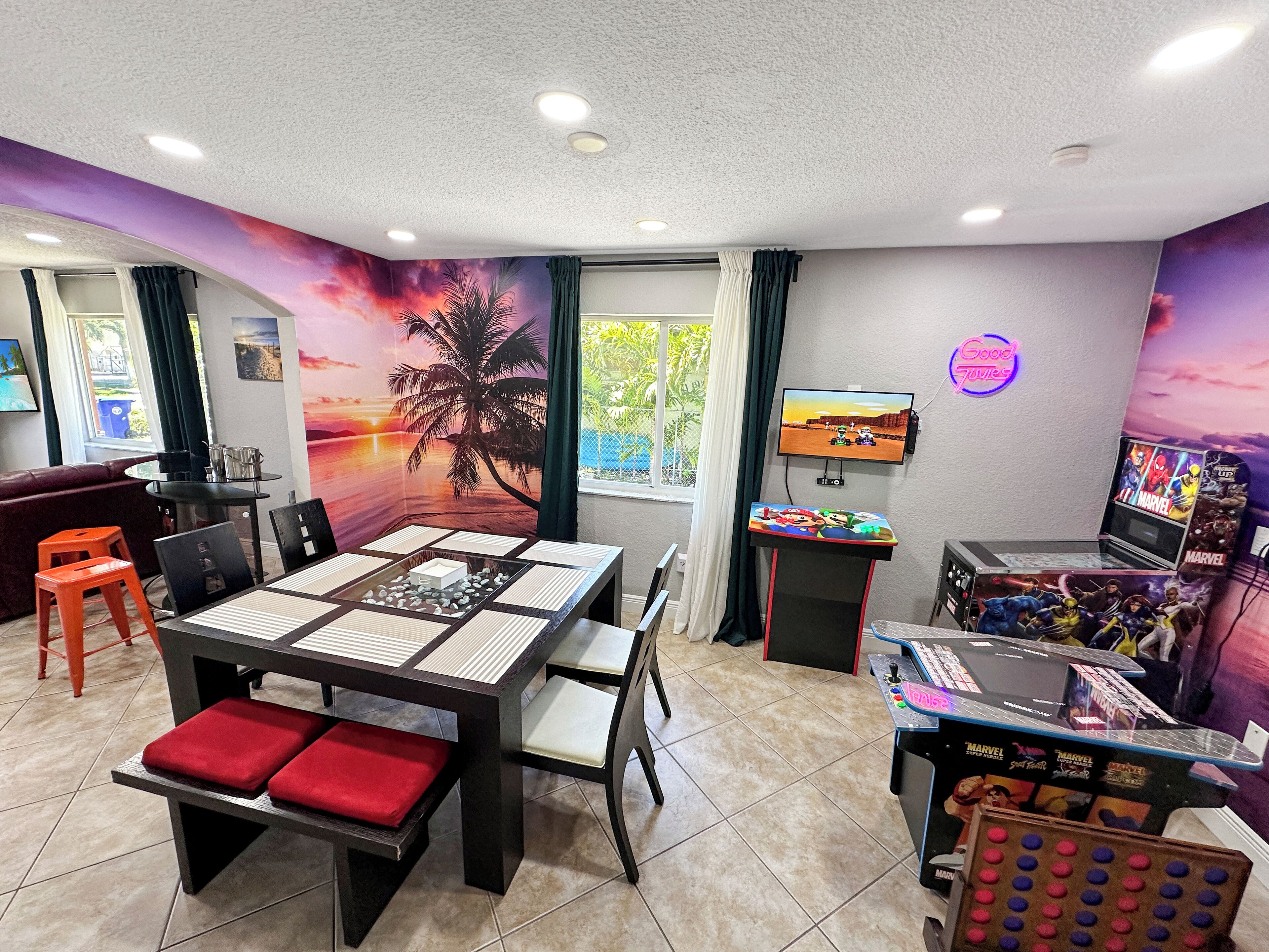 Una habitación con una mesa de comedor, sillas, un televisor y una zona de juegos con mesa y sillas.