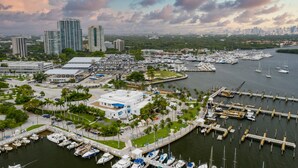 A marina with numerous boats docked, surrounded by buildings and greenery.