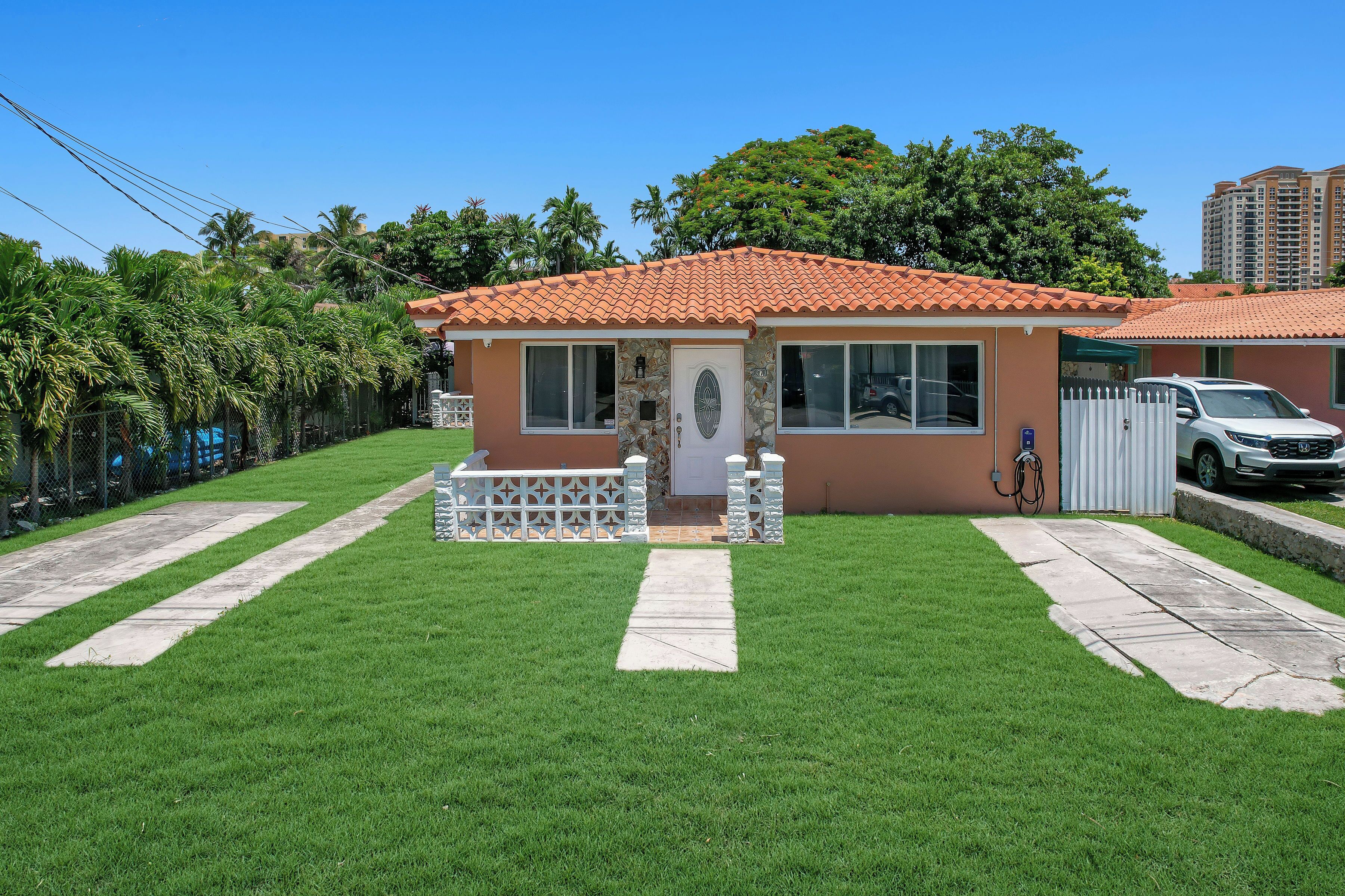 A small house with a tiled roof, a front porch, and a paved driveway.