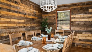 Un comedor rústico de madera con una gran mesa dispuesta para seis personas, rodeada de sillas de madera.