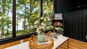 Una recepción con una cesta de mimbre que contiene un jarrón de flores blancas y un cartel que dice 'bienvenidos al lago'.