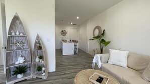 Ein modernes Wohnzimmer mit einer Couch, einem dekorativen Holzregal und einem Essbereich im Hintergrund.
