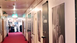 A hotel corridor with doors, posters, and a red carpet. - Hotel CAMELOT (Fujikawaguchiko)