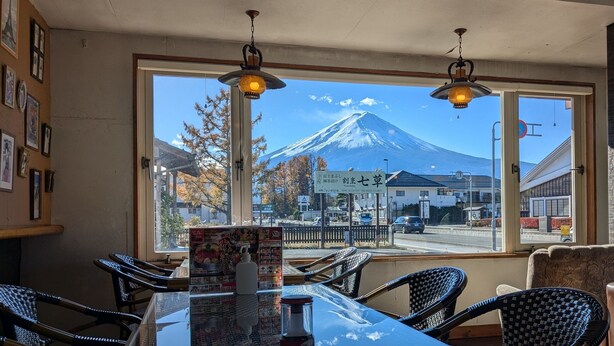 A restaurant with a view of a snow-capped mountain, wicker chairs, and a menu board. - Hotel CAMELOT (Fujikawaguchiko)