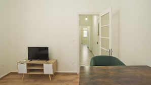A room with a wooden desk, a television, and a green chair. - Aristea in Athens With 2 Bedrooms and 1 Bathrooms (Athens)