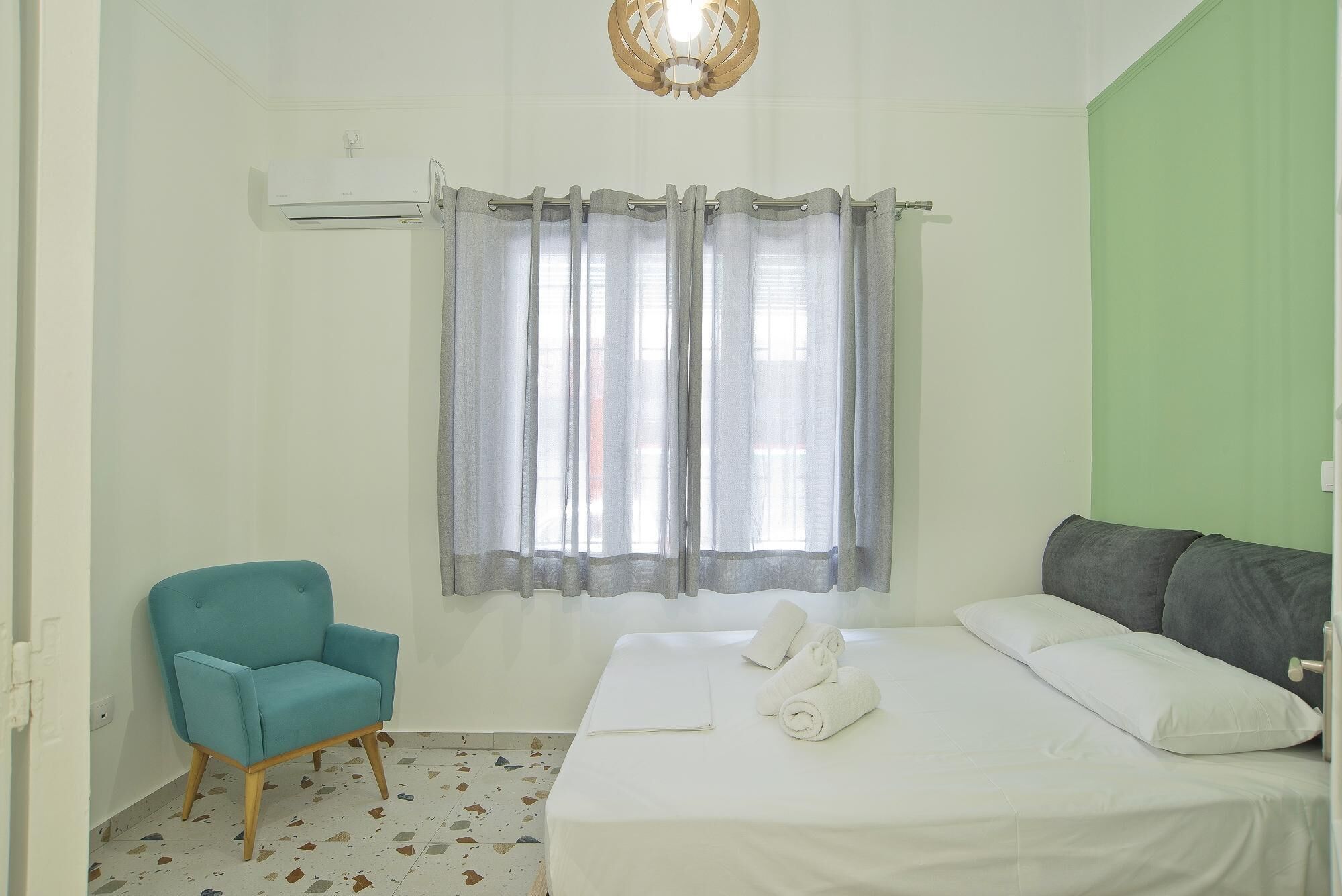 A bedroom with a bed, a chair, and a window with curtains.