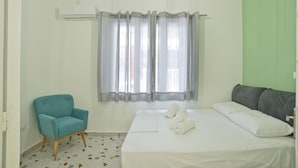 A bedroom with a bed, a chair, and a window with curtains. - Aristea in Athens With 2 Bedrooms and 1 Bathrooms (Athens)