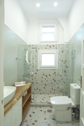 A compact bathroom with a glass-enclosed shower, a toilet, and a sink.