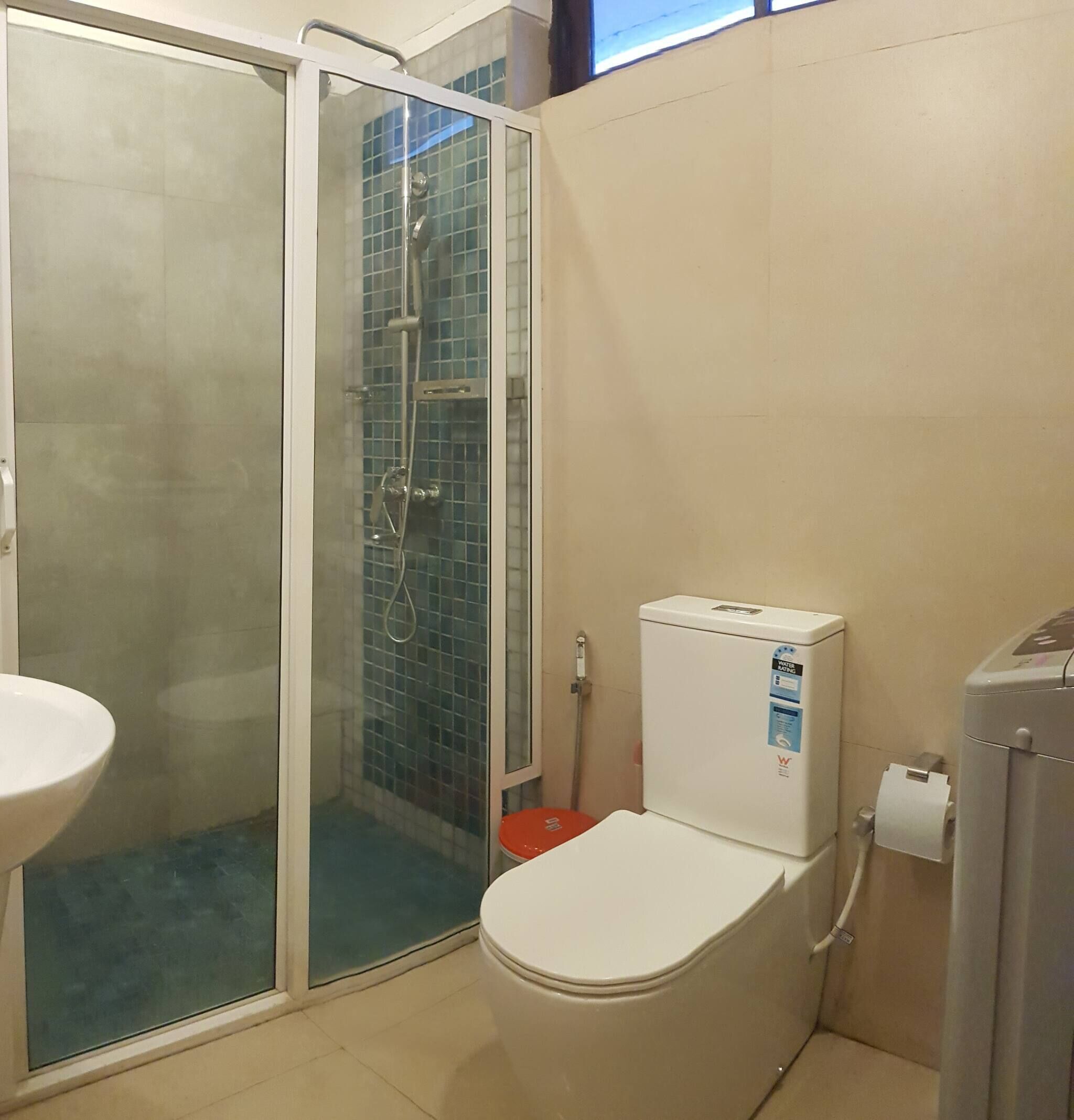 A bathroom with a glass-enclosed shower, a toilet, and a sink.