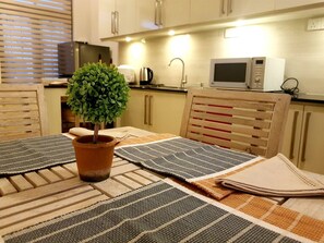A kitchen with wooden cabinets, a microwave, and a potted plant on the table. - MyHavelock Town Studio Apt, with Own Pvt Gate Parking in Main City (Colombo)