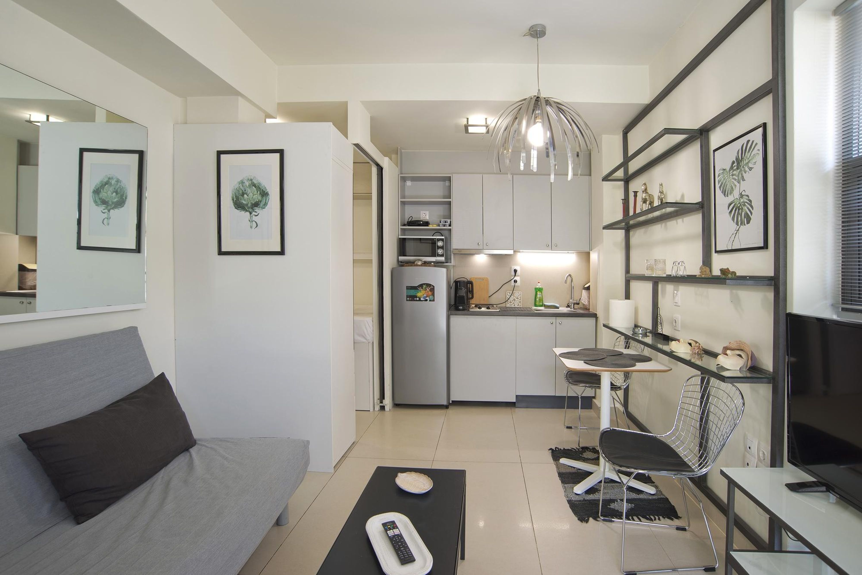 Un espacio habitable compacto con kitchenette, comedor y sofá.