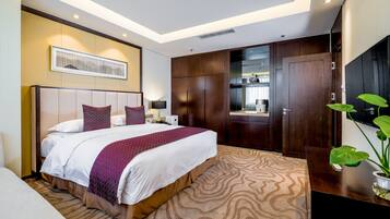 A hotel room with a large bed, a TV, a wardrobe, and a plant.